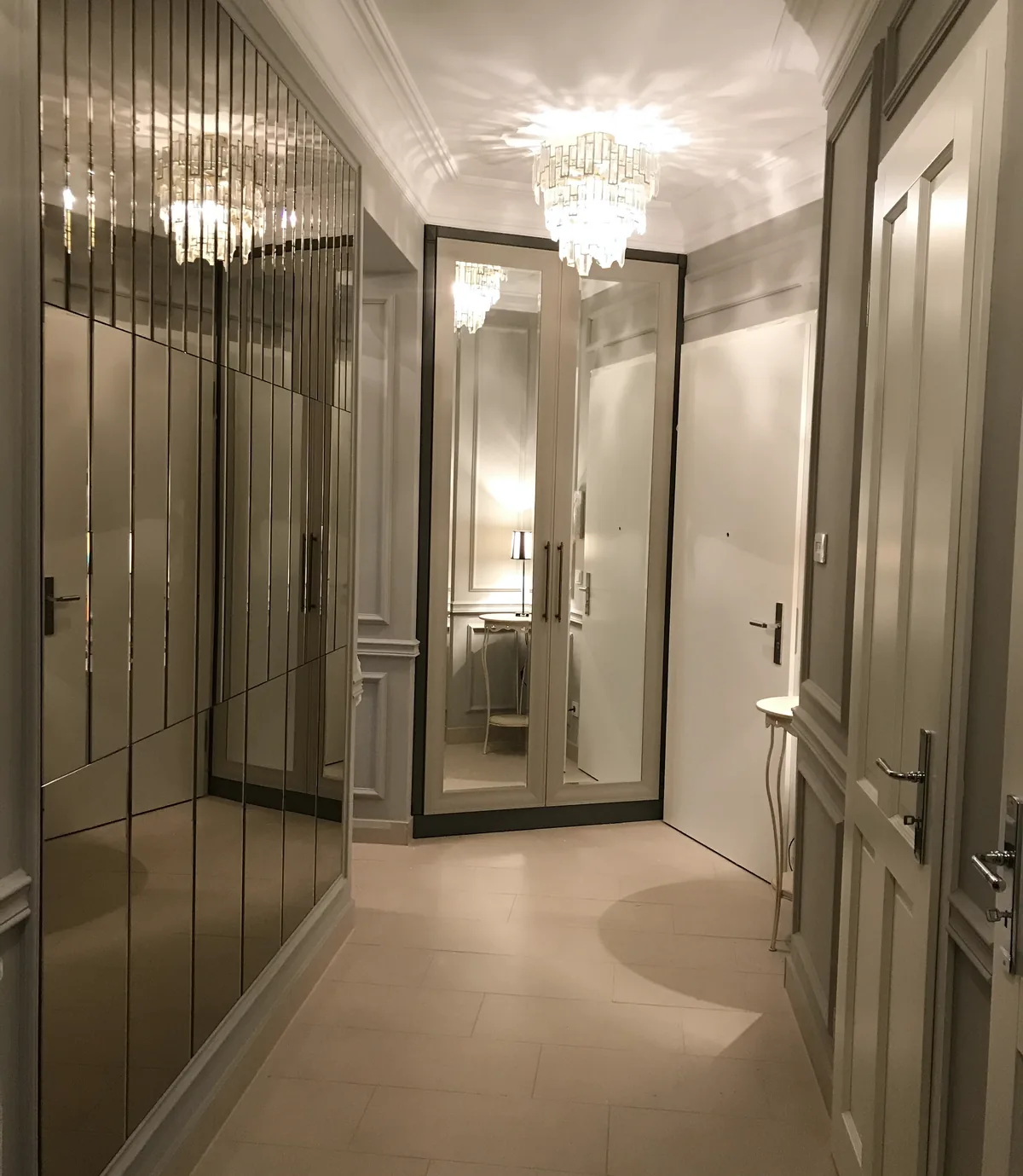 Schmaler Flur mit einem Einbauschrank mit Spiegeltüren in der Ecke, Kristalllüster an der Decke, Konsolentisch und Tür rechts