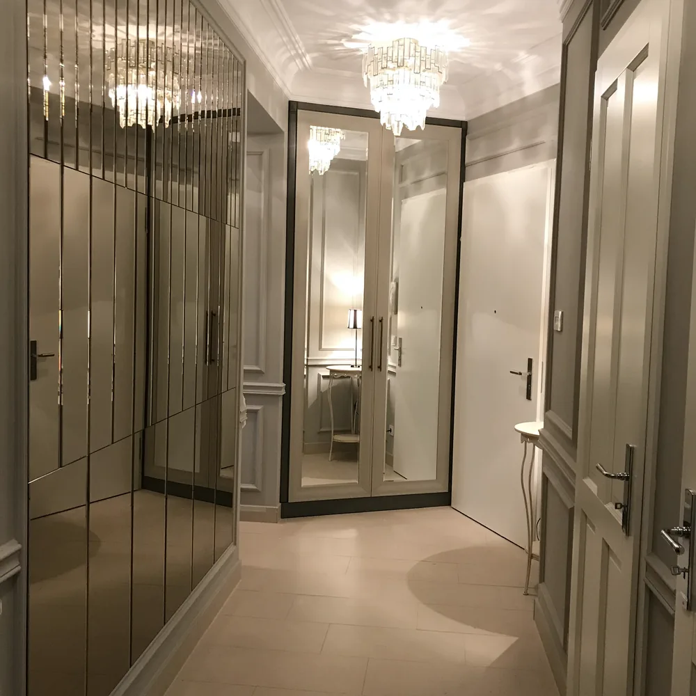 Schmaler Flur mit einem Einbauschrank mit Spiegeltüren in der Ecke, Kristalllüster an der Decke, Konsolentisch und Tür rechts